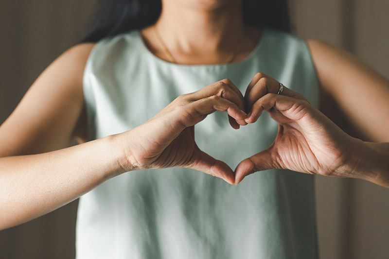 Close up of woman making heart shape for Valentines day, Mothers day and Breast Cancer Awareness month for Healthcare of International Women day