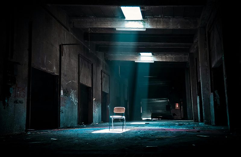Creepy dark room with empty chair sitting in room center.