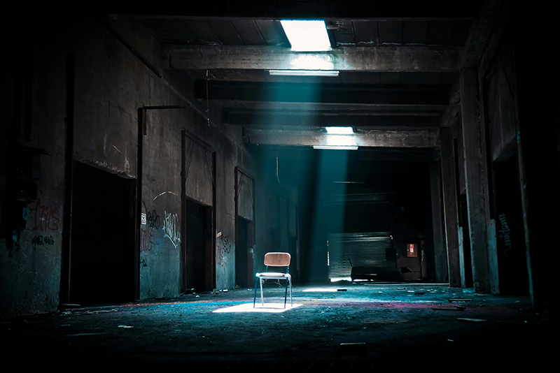 Creepy dark room with empty chair sitting in room center.